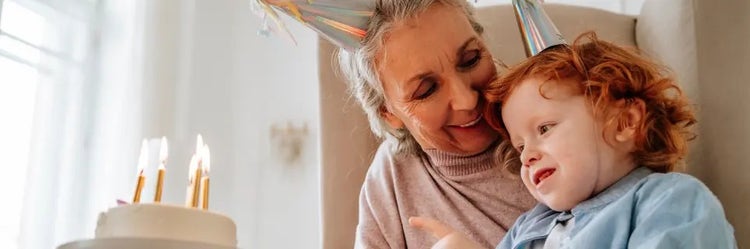 Image of a grandmother looking at a child blowing out candles on a cake (not real patients)