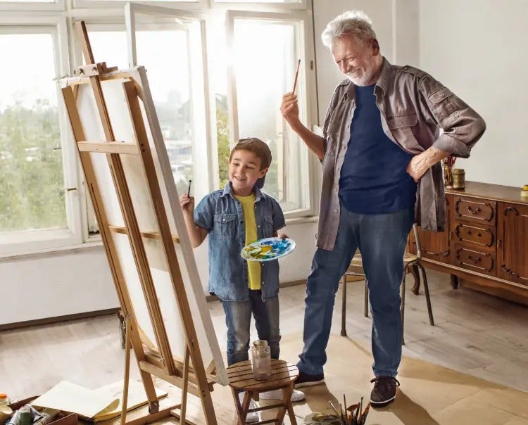 Image of an older man and a boy painting on an easel (not real patients) mobile