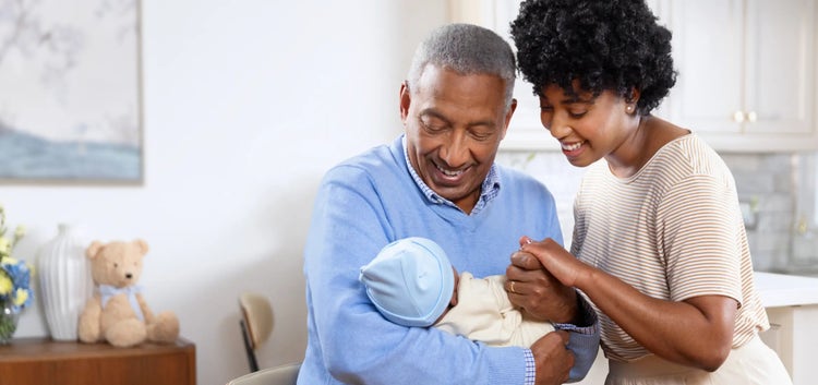 Image of a grandfather and mother looking at a baby (not real patients)