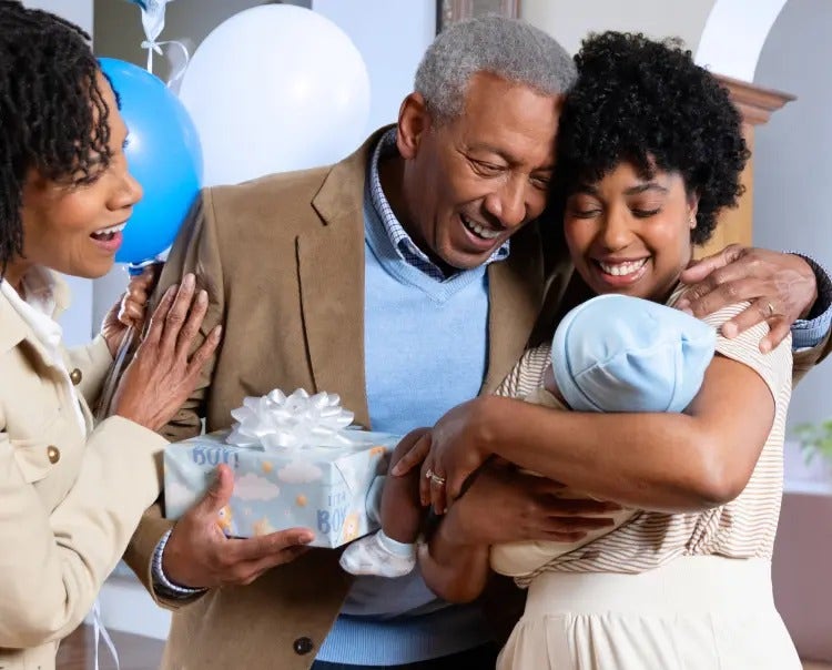 Image of a grandfather and grandmother looking at a mother holding a baby (not real patients) mobile