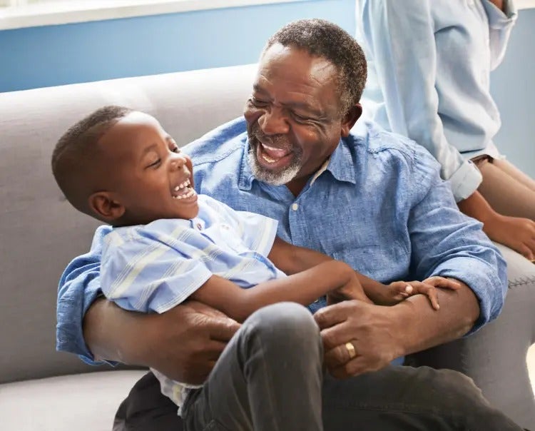 Image of an older man smiling and playing with a child (not real patients) mobile