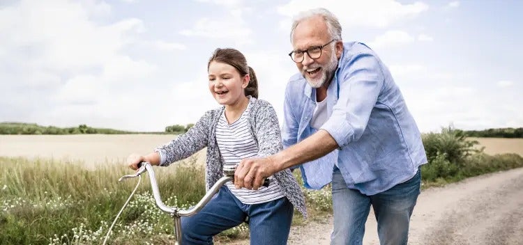 Image of an older man helping a young girl ride a bike (not real patients) mobile