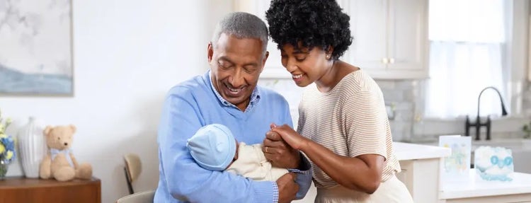 Image of a grandfather and mother looking at a baby (not real patients)