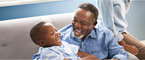 Image of an older man smiling and playing with a child (not real patients)