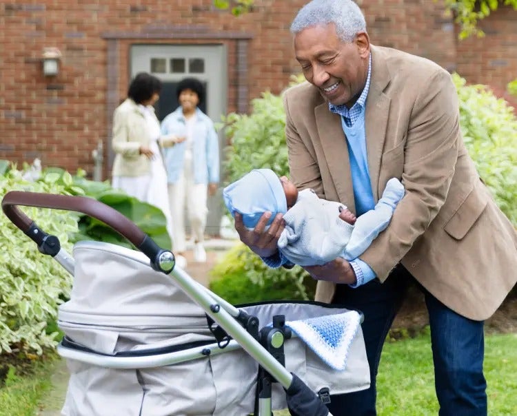 Image of a grandfather placing a baby in a carriage, as a grandmother and mother talk in the background (not real patients) mobile