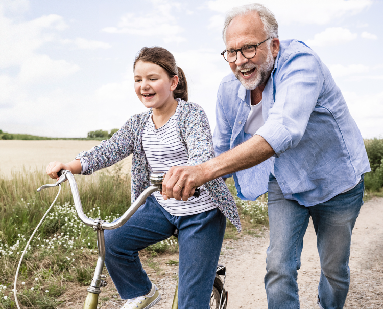 Image of an older man helping a young girl ride a bike (not real patients) mobile