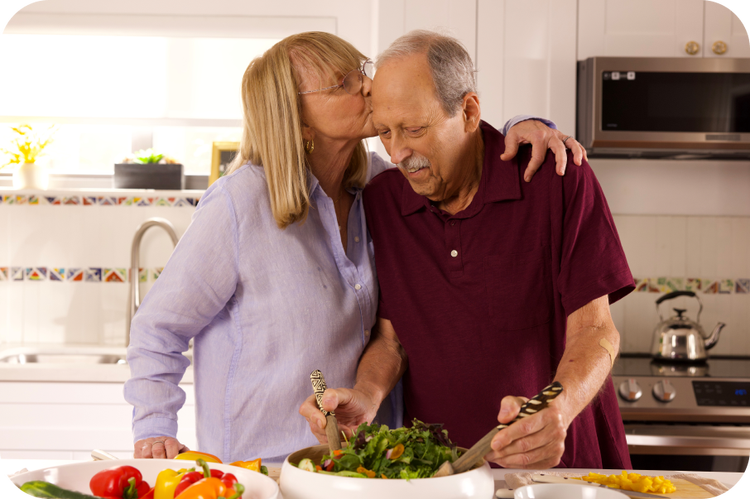 Real ELREXFIO (elranatamab-bcmm) patient Louis in a kitchen with his care partner, Charlene
