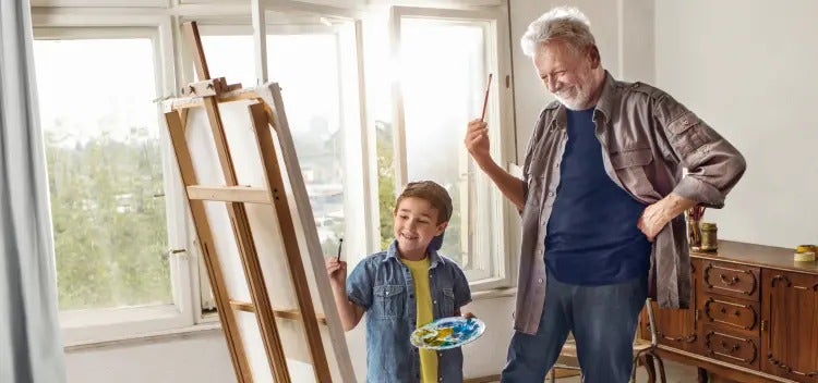 Image of an older man and a boy painting on an easel (not real patients) mobile