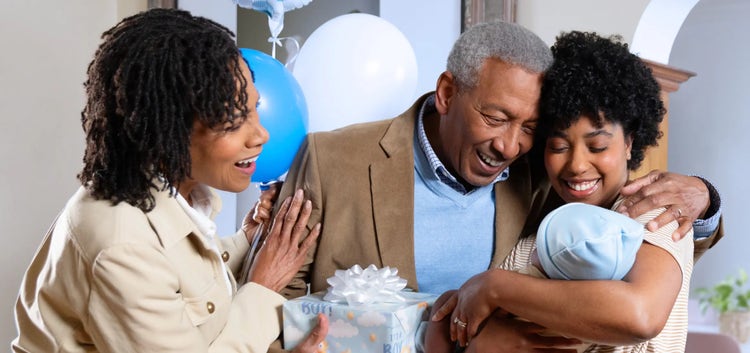 Image of a grandfather and grandmother looking at a mother holding a baby (not real patients)