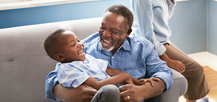 Image of an older man smiling and playing with a child (not real patients)