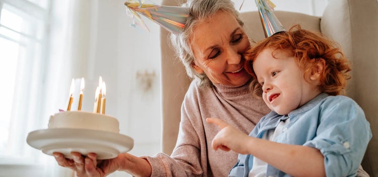 Image of a grandmother looking at a child blowing out candles on a cake (not real patients)